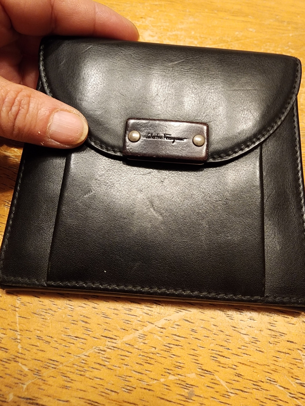 black leather Salvatore Ferragamo bifold wallet features a branded snap closure